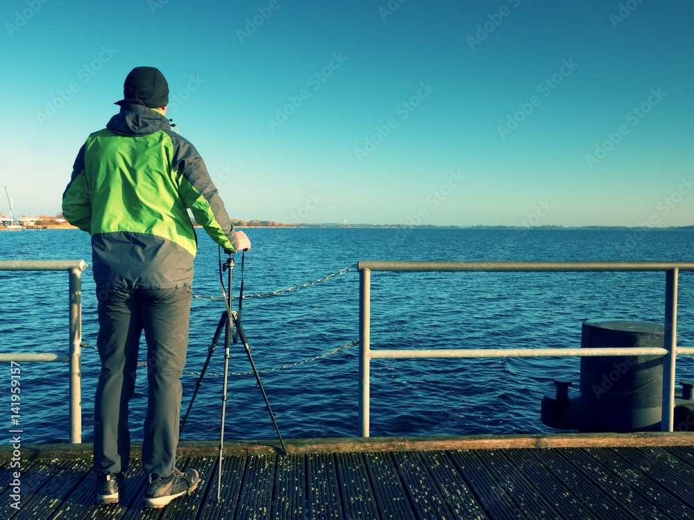 Alone artist on wooden sea bridge.  Man on wooden sea mole
