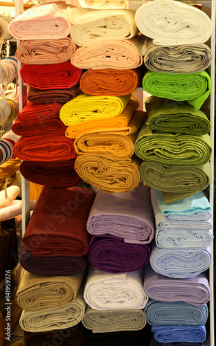 shelf with several rolls of colored fabric for tailors