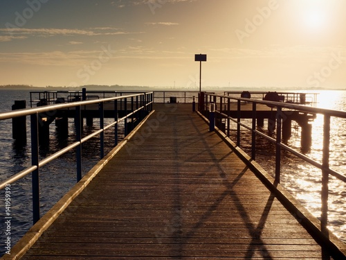 Long wooden pier at coast, cold morning, peaceful silent day © rdonar