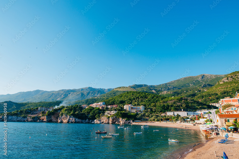 Przno, Montenegro. Beach, sun beds and umbrellas on the beach, the beach line.