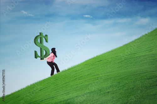 Woman carrying dollar symbol on hill