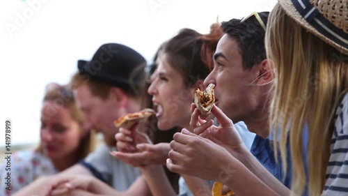 Close up of group of young multi-ethnic friends enjoying at a party while eating pizza photo