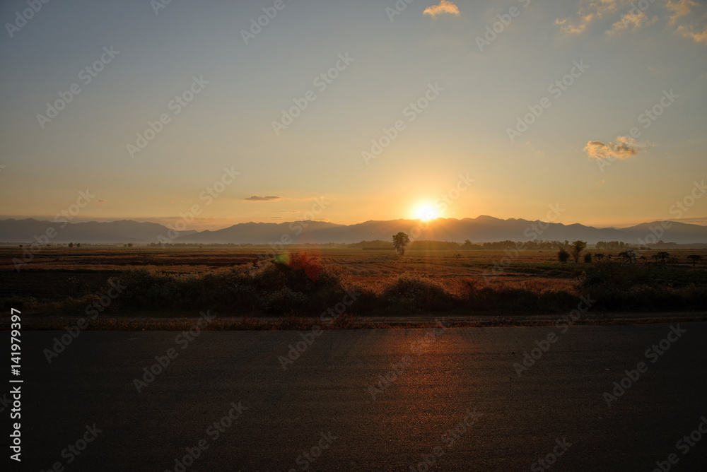 Country road side view and mountain background at sunrise