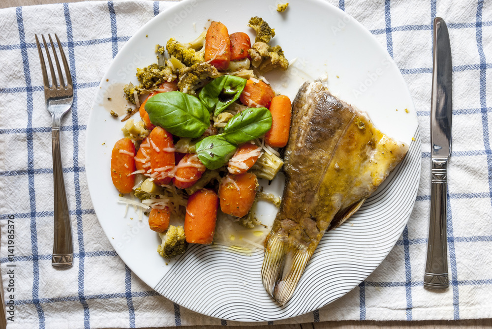 Bass baked with broccoli, carrots and basil leaves