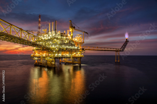 Offshore oil and rig platform in sunset or sunrise time. Construction of production process in the sea.