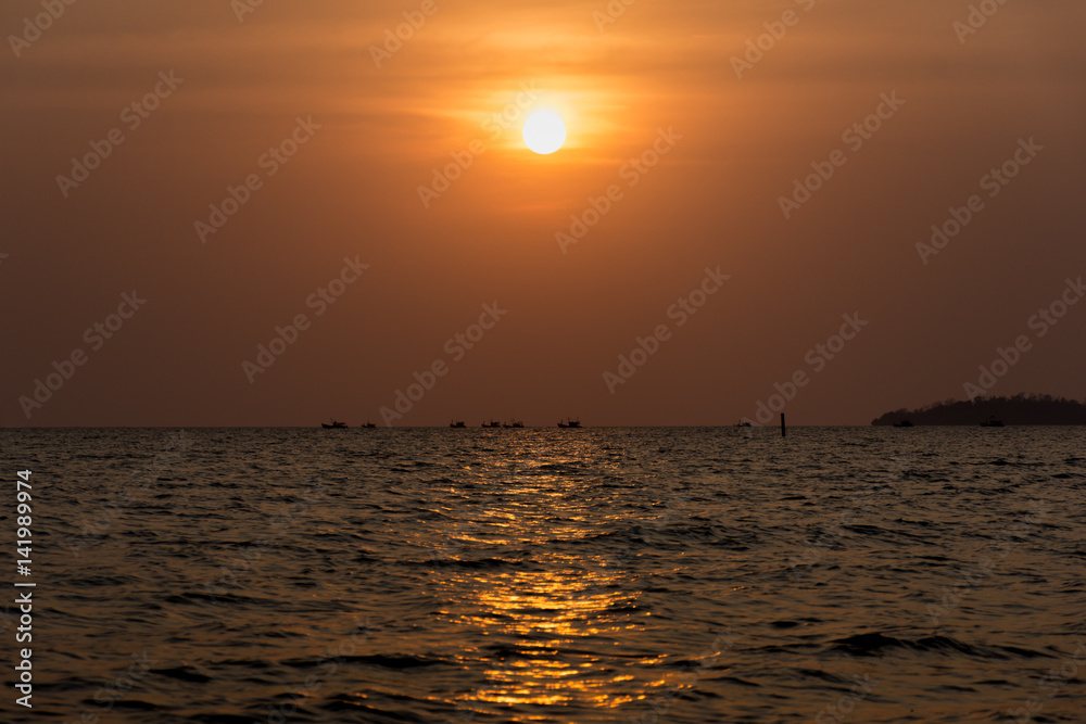 Fototapeta premium Sun setting a fishing boats head out to sea.