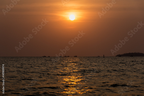 Foto Sun setting a fishing boats head out to sea.