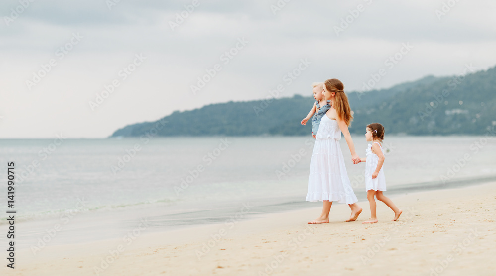 Happy family mother and children on beach by sea in summer Happy family mother and children on beach by sea in summer