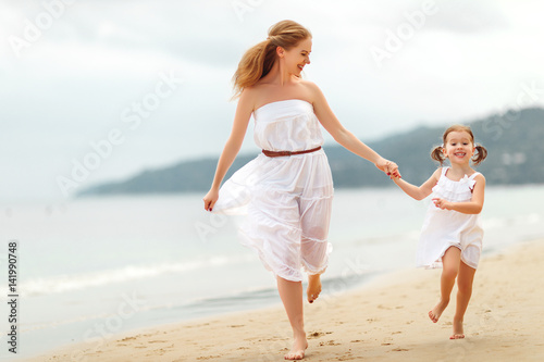 happy family mother and daughter run, laugh and play at beach