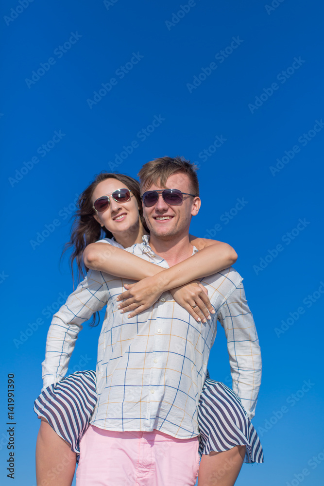 Piggyback. Young man carrying girl against clear sky Piggyback. Young man carrying girl against clear sky