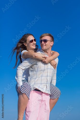 Piggyback. Guy carrying on his back girl against sky