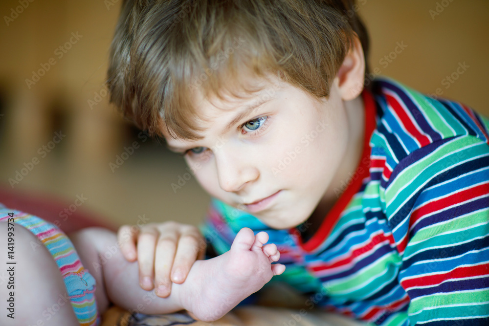 Little kid boy kissing and playing with foot of newborn baby. Little kid boy kissing and playing with foot of newborn baby.