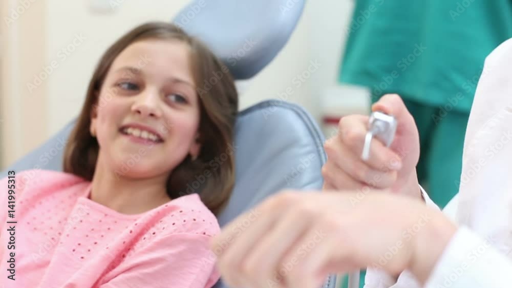 Young female dentist showing dental instruments to a little girl, playing with instruments Young female dentist showing dental instruments to a little girl, playing with instruments