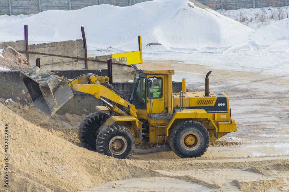 Yellow excavator loads sand