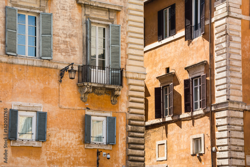 Old yellow facades of Italian houses with open wooden windows in the historical center of Rome