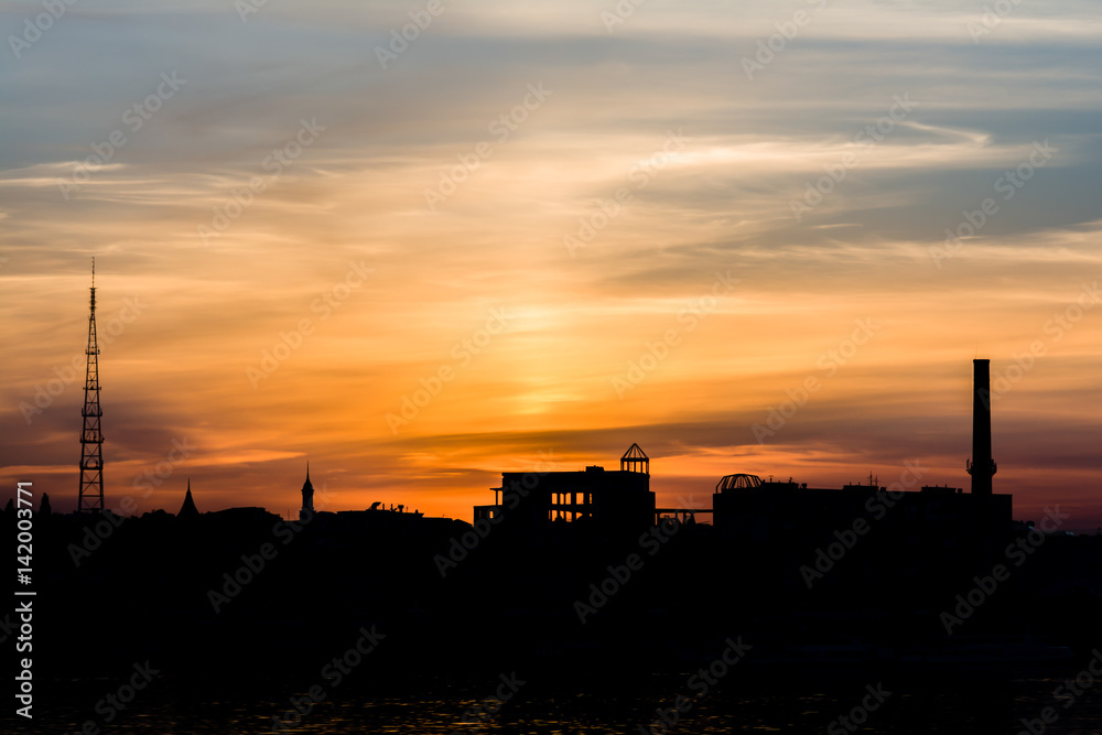 Dramatic sunset over the city silhouette near water