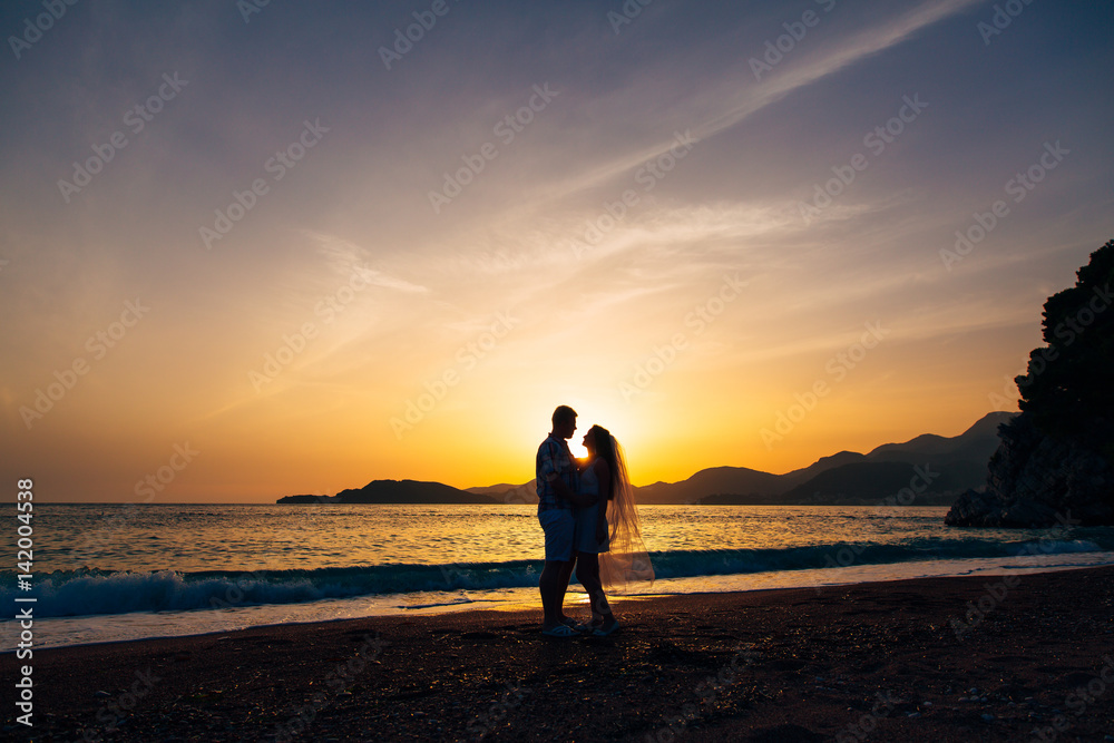 Silhouette of a newlywed couple at the sea at sunset. Wedding in Montenegro. Silhouettes of the couple, the bride and groom.