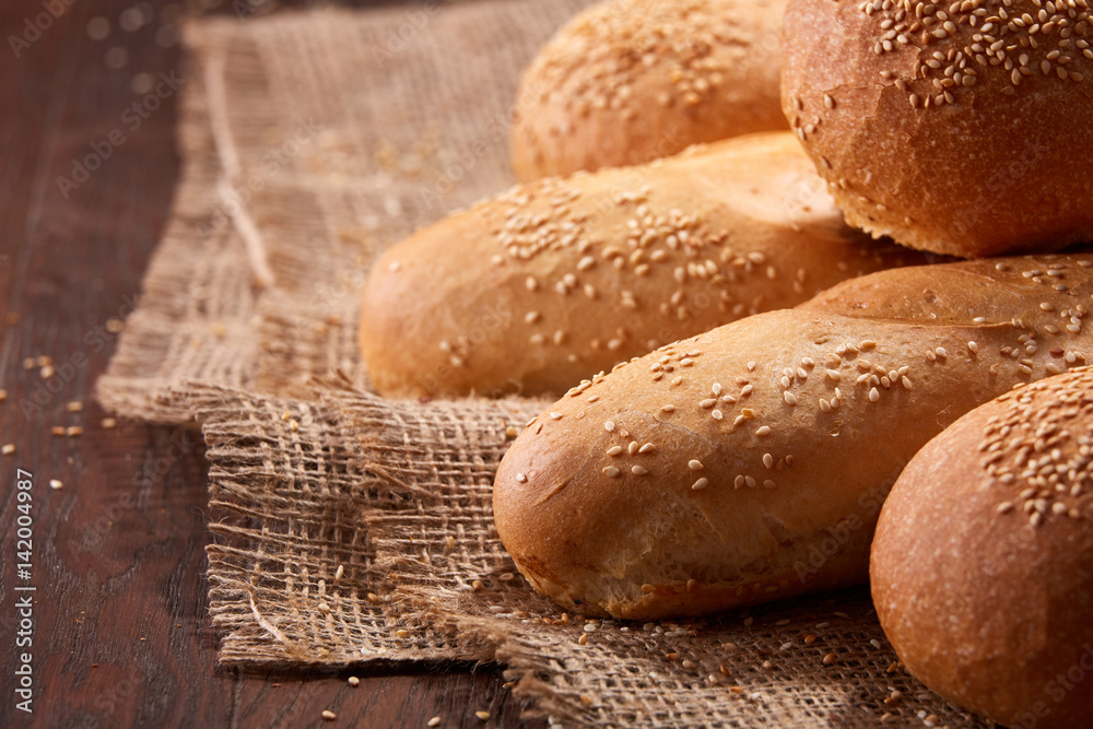 Freshly baked baguette bread and rulls on a burlap napkin on a wooden background. Close up