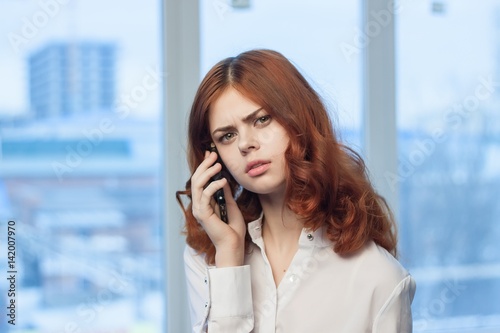 woman with phone in the office near the window