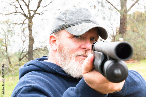 Man With Beard Aiming Shotgun photo