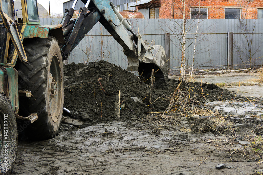 Fototapeta premium An old Soviet tractor digs and loads waste stone processing near the shop