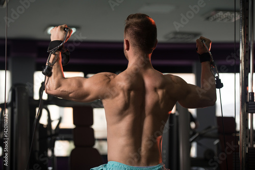 Muscular Man Exercising Shoulders On Machine