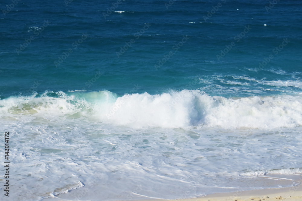 A small ocean wave on the beach during a bright sunny day. New Providence, Nassau, Bahamas.