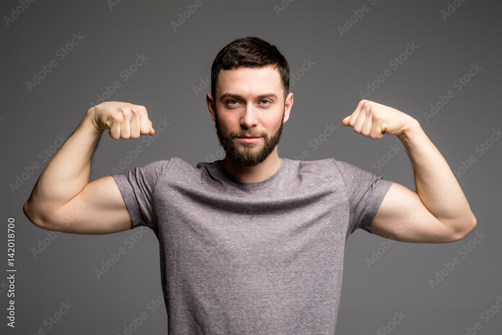 Portrait of a man in shirt showing his muscles over gray background Portrait of a man in shirt showing his muscles over gray background