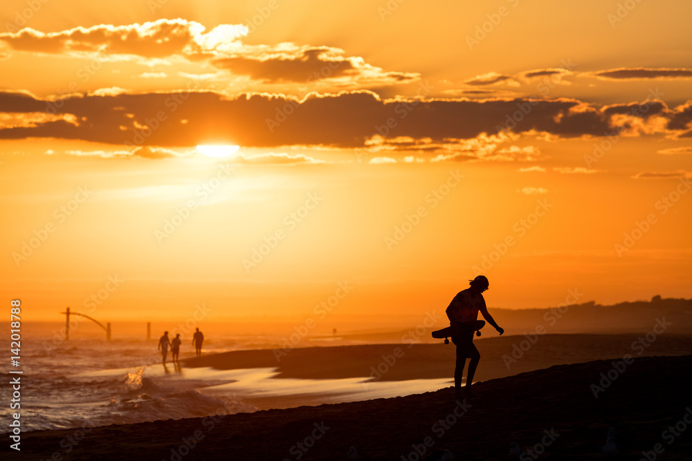 Skateboarder at beach during Sunset