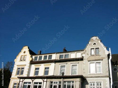 Schöne alte Fassade eines symmetrischen alten Wohngebäude in Beige und Naturfarben vor strahlend blauem Himmel im Sommer bei Sonnenschein im Staatsbad Bad Salzuflen bei Herford in Ostwestfalen-Lippe photo