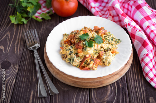 Fried eggs with tomato on dark wooden table