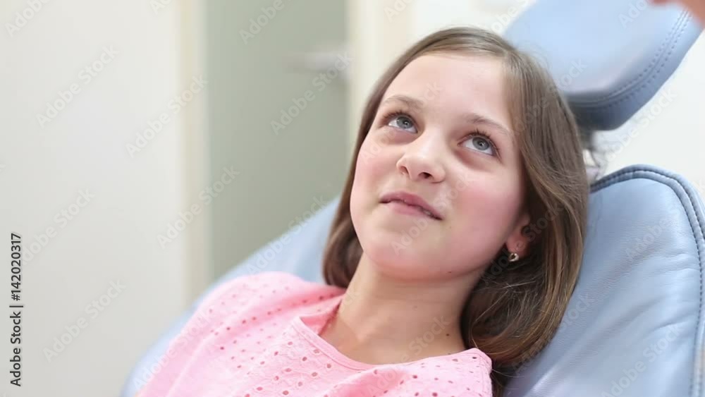 Cute little girl sitting in the dental chair, talking with dentist Cute little girl sitting in the dental chair, talking with dentist
