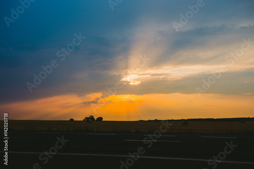 Traktor at sunset in the field. Silhouette.