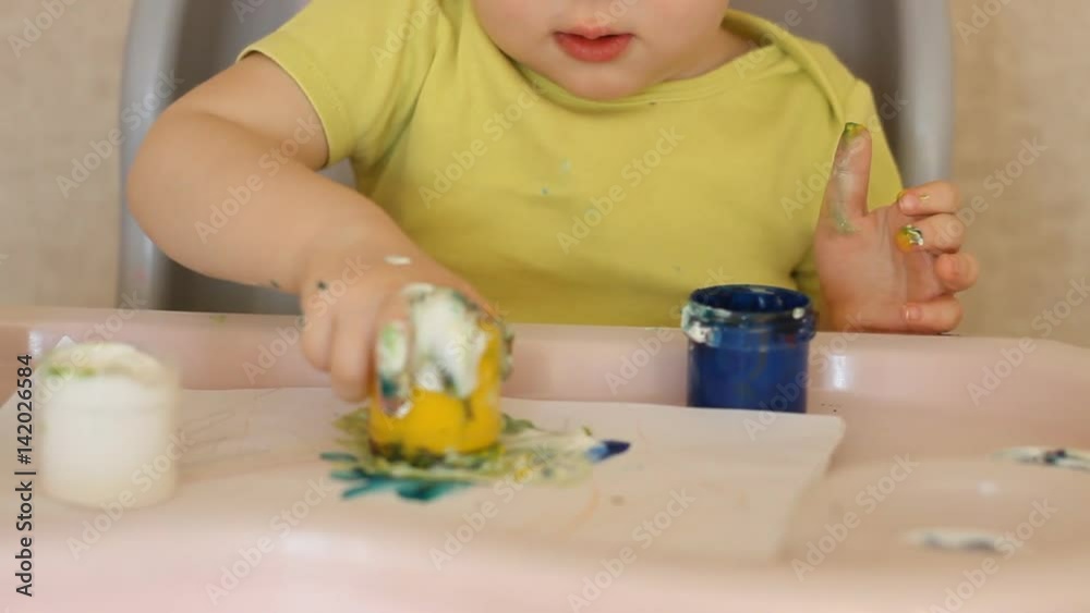 The child paints with his fingers. The child paints with his fingers.