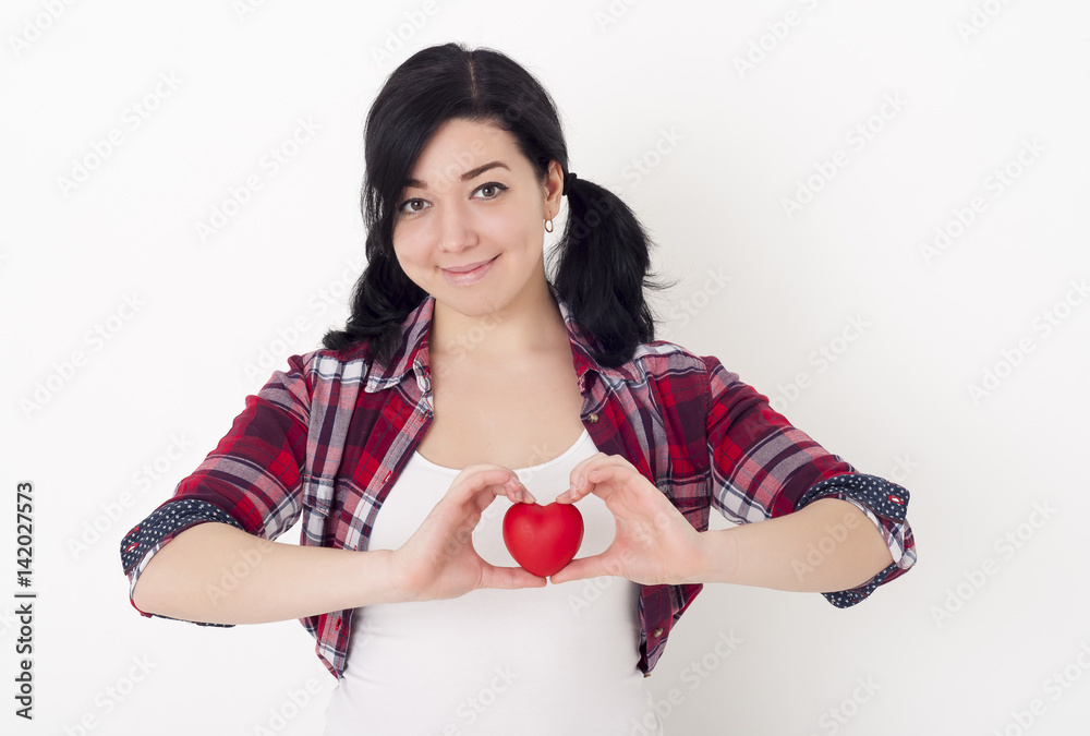 Young teenage girl with pigtails on her head holds a red heart in her hands and smiles Young teenage girl with pigtails on her head holds a red heart in her hands and smiles