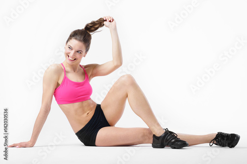 Young attractive tanned slender girl performs sports exercises.