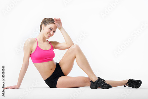 Young attractive tanned slender girl performs sports exercises.
