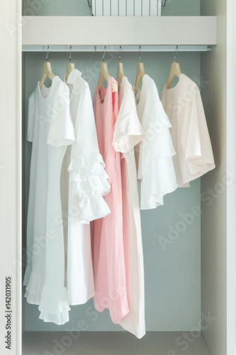 Pastel woman cloths hanging on rail in wardrobe