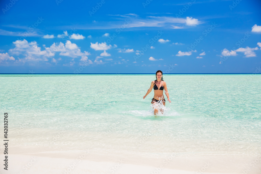 Attractive young woman enjoys Maldivian beach running in the ocean water Attractive young woman enjoys Maldivian beach running in the ocean water