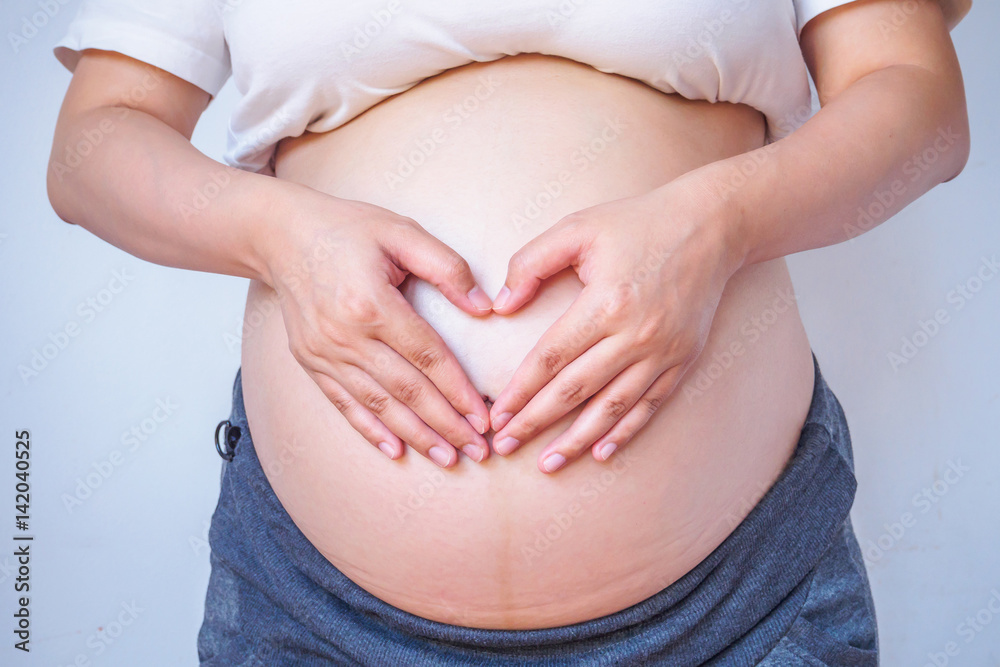pregnant woman hands forming heart on her belly pregnant woman hands forming heart on her belly