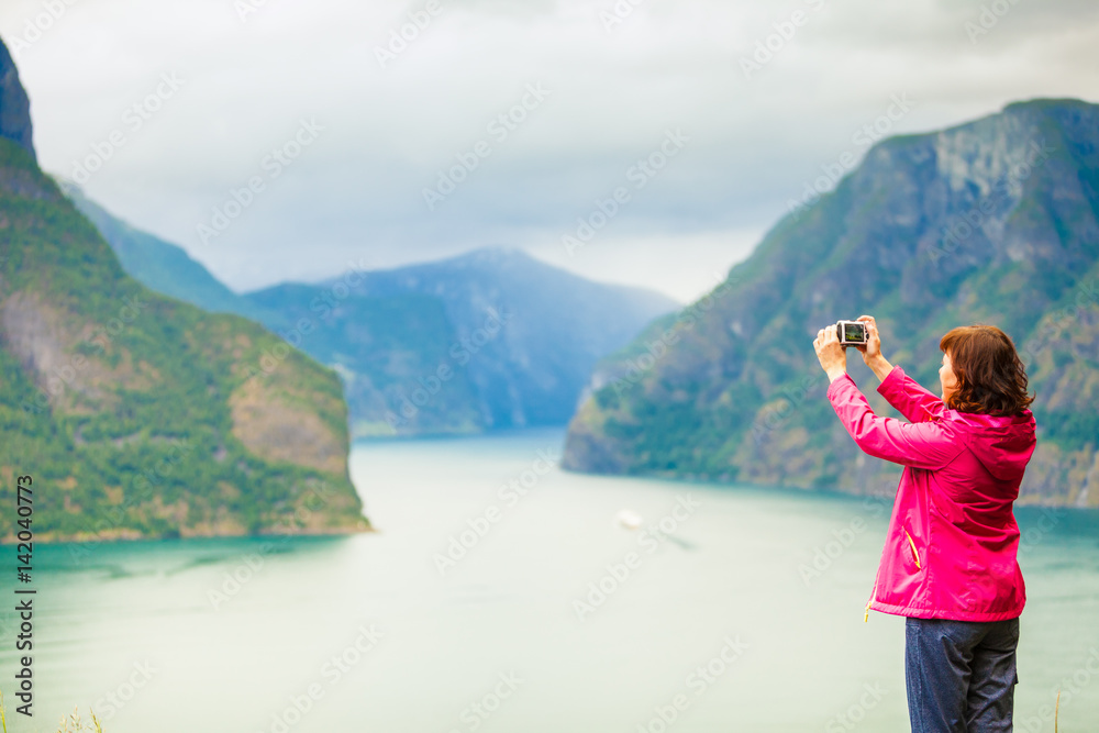 Female tourist taking photo at norwegian fjord