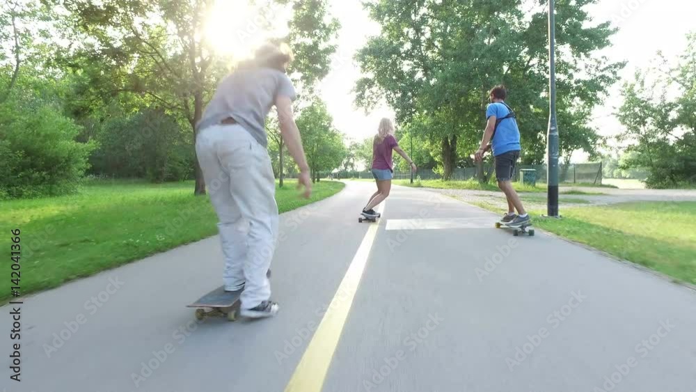 Back view of woman and two guys skateboarding Back view of woman and two guys skateboarding