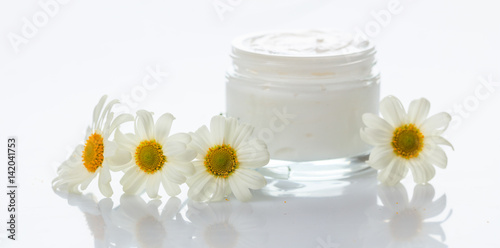 Moisturizing cream and chamomile on white background