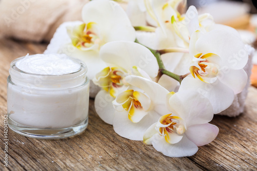 Moisturizing cream and orchid on wooden background