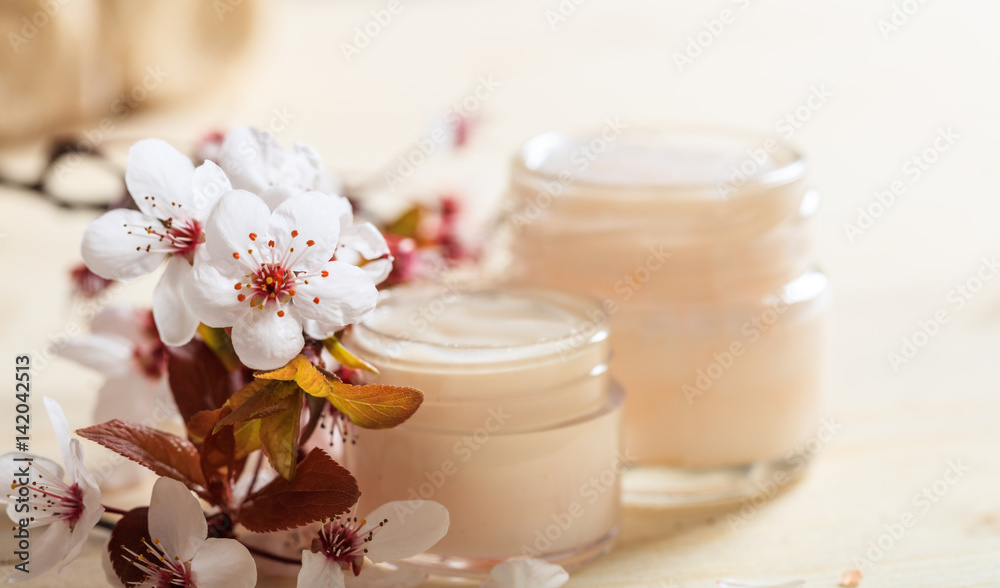 Moisturizing cream and cherry blooms on wooden background Moisturizing cream and cherry blooms on wooden background
