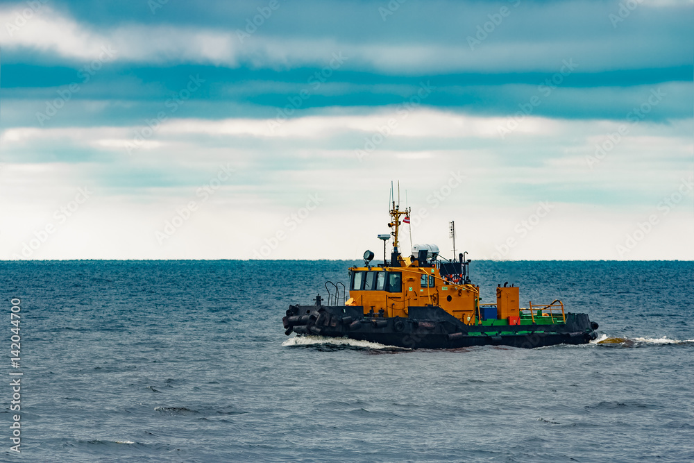 Fototapeta premium Small orange tug ship moving from the Baltic sea