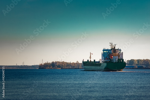 Green cargo ship entering a port of Riga, Europe