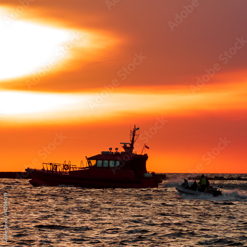 Pilot ship and the dinghy on speed during hot sunset, Latvia