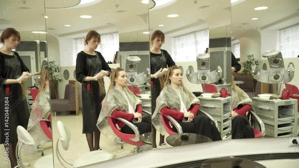 The hairdresser preparing wet hair for a haircut in front of the mirror