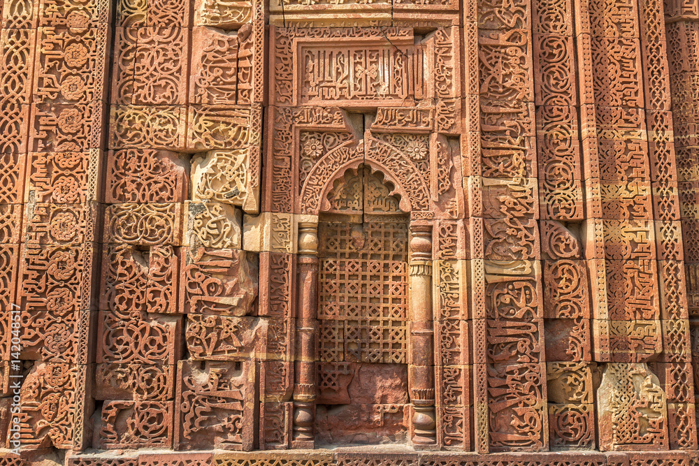 Ancient carved red sandstone background at the Qutb Minar medieval monuments.